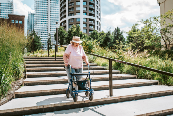 Senior woman walking down the stairs with rollator, running errands.