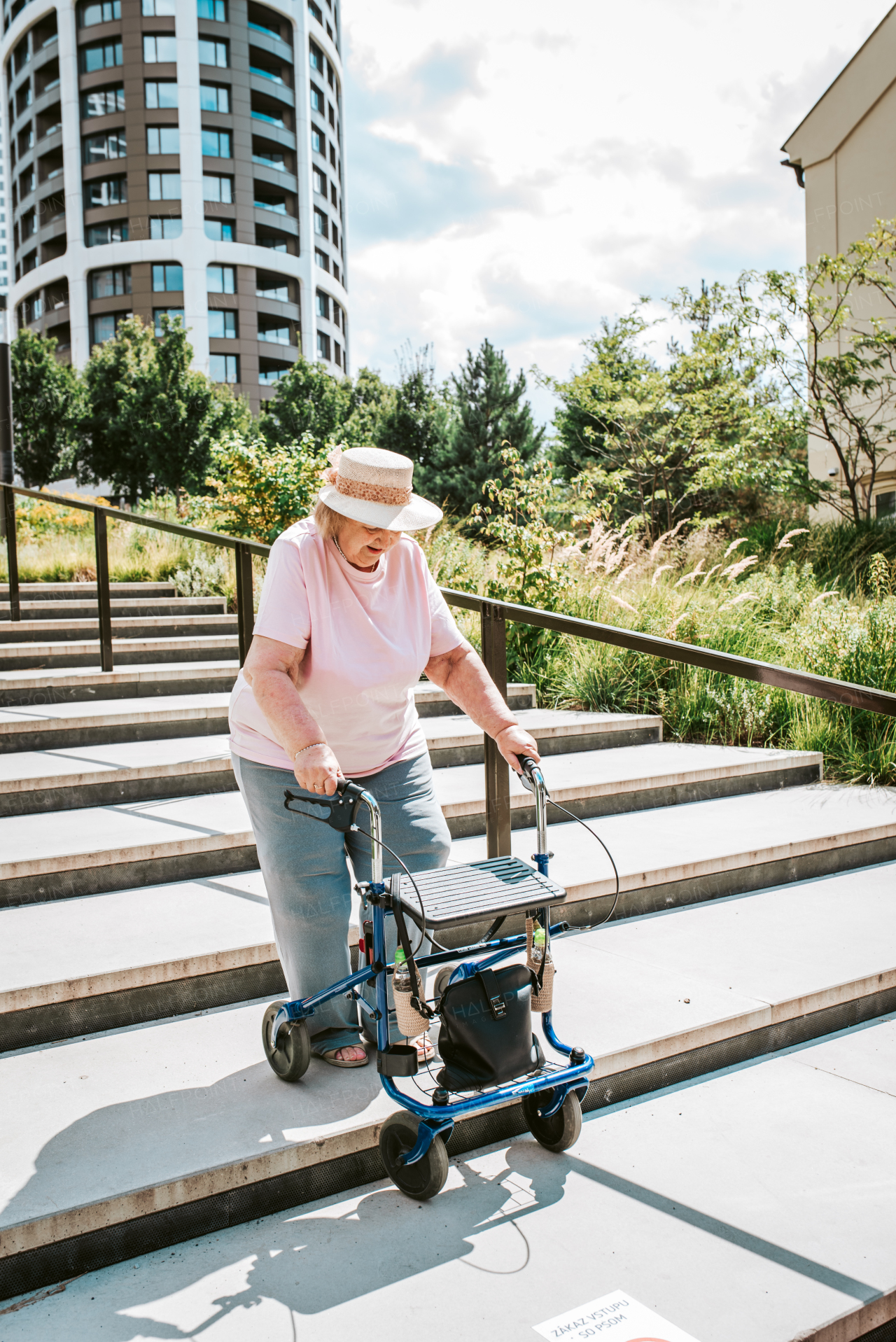 Senior woman walking down the stairs with rollator, running errands.