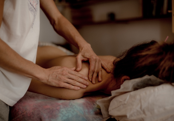 A close-up of hands of a masseur massaging back of a young woman, traditional chinese medicine.