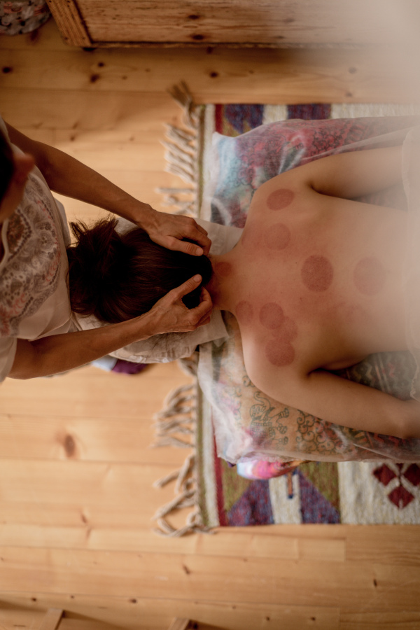 A close-up of hands of a masseur massaging back of a young woman, traditional chinese medicine.