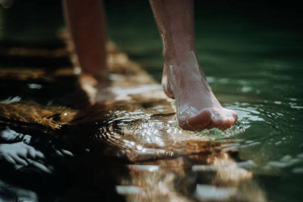 Close-up of barefoot legs walking in the lake shore. Concept of healthy feet.