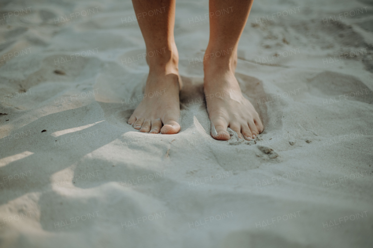 Close-up of barefoot legs walking in the sand. Concept of healthy feet.