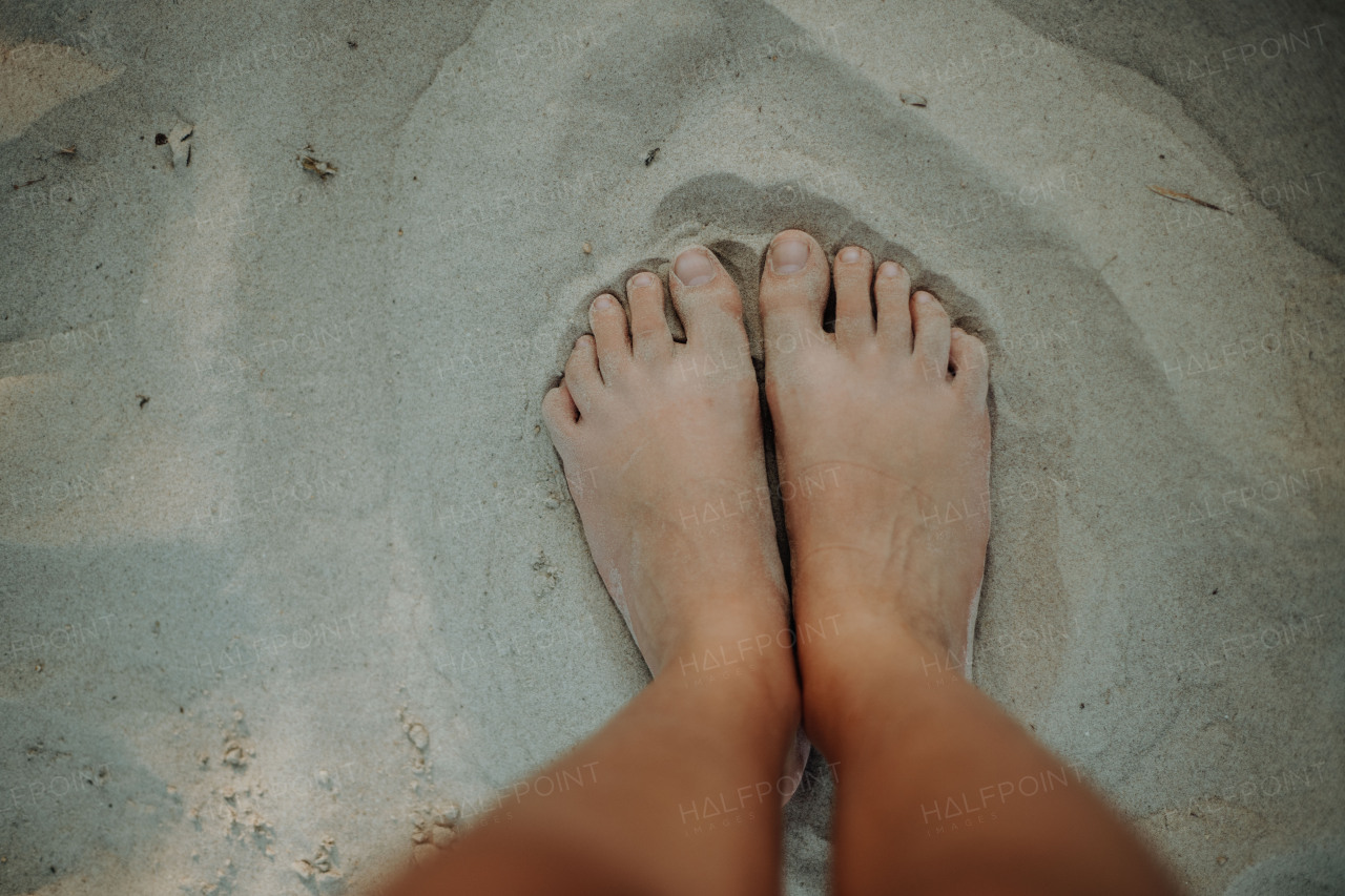 Close-up of barefoot legs walking in the sand. Concept of healthy feet.