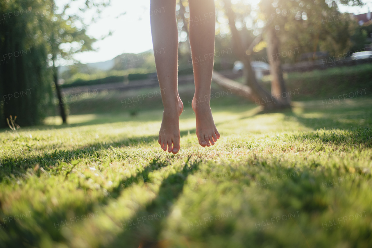 Close-up of barefoot legs jumping in the lawn. Concept of healthy feet.