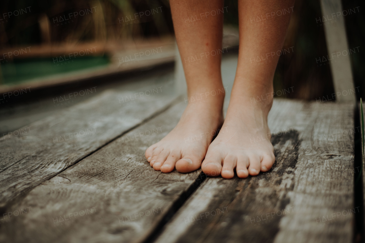 Close-up of barefoot legs standing on pier in lake. Concept of healthy feet.