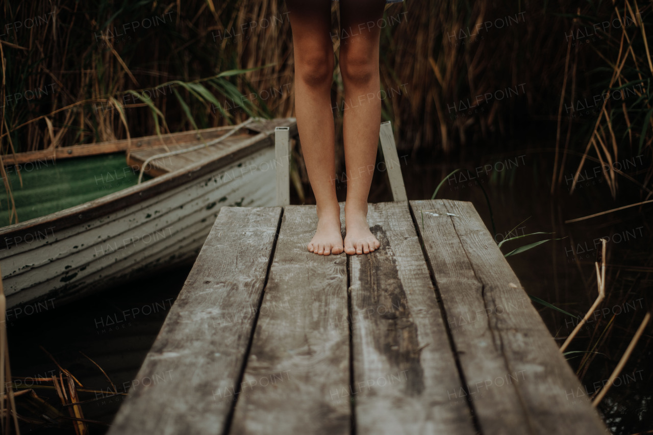 Close-up of barefoot legs standing on pier in lake. Concept of healthy feet.