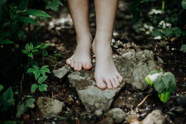 Close-up of barefoot legs walking in the forest. Concept of healthy feet.