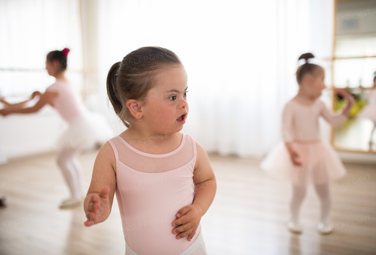 Little girl with down syndrome at a ballet class in dance studio. Concept of integration and education of disabled children.