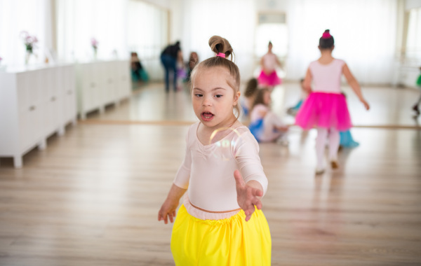 Little girl with down syndrome at a ballet class in dance studio. Concept of integration and education of disabled children.