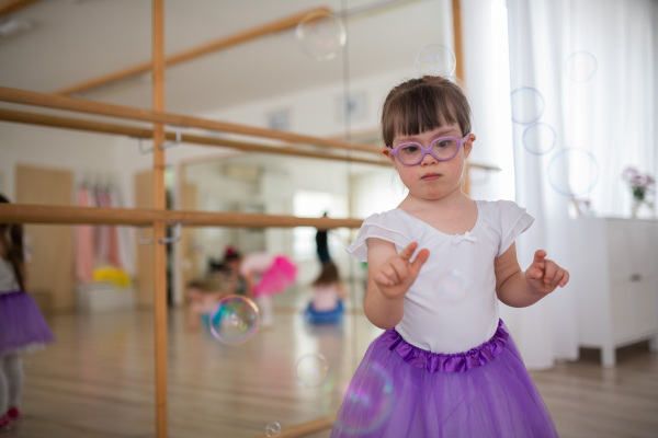 Little girl with down syndrome at a ballet class in dance studio. Concept of integration and education of disabled children.