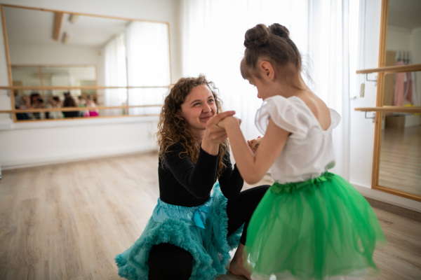 Little dissabled girl learning ballet with dance lecteur in a ballet studio. Concept of integration and education of disabled children.