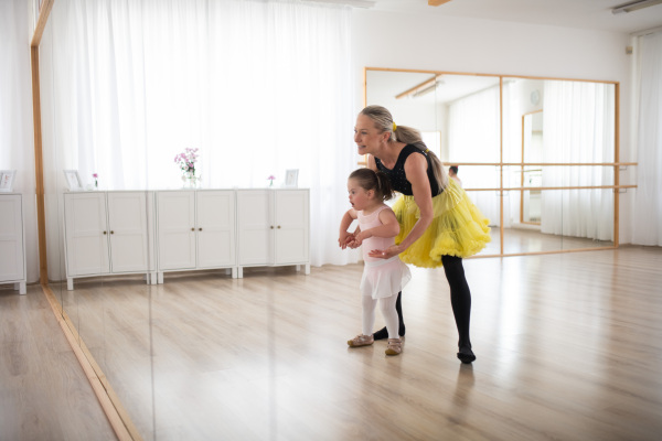 Little girl with down syndrome learning ballet with dance lecteur in a ballet studio.