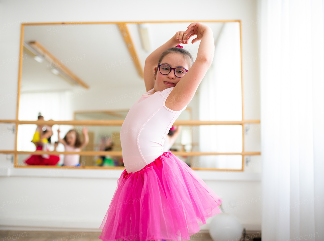 Little girl with down syndrome at a ballet class in dance studio. Concept of integration and education of disabled children.