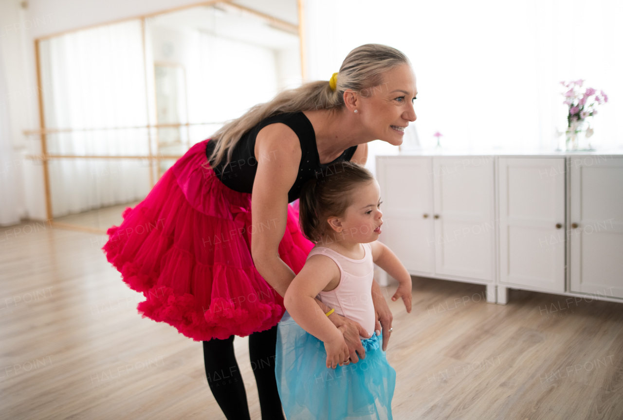 Little girl with down syndrome learning ballet with dance lecteur in a ballet studio.