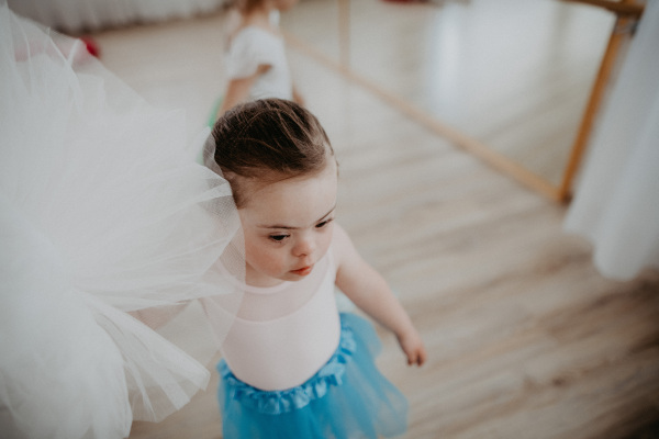 High angle view of little girl with down syndrome at a ballet class in dance studio. Concept of integration and education of disabled children.