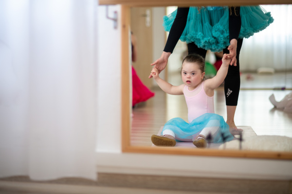 Little girl with down syndrome learning ballet with dance lecteur in a ballet studio.