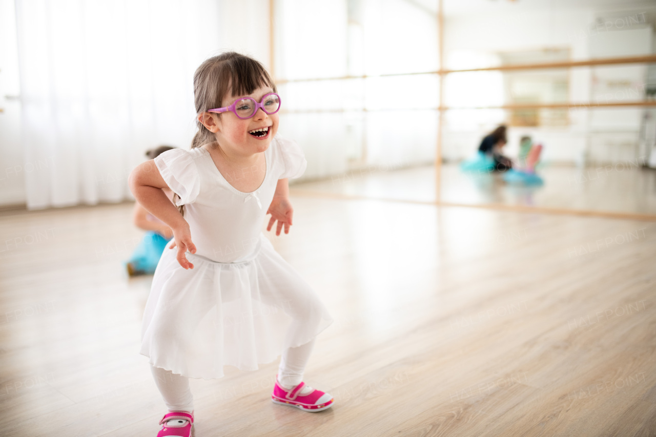 Little girl with down syndrome at a ballet class in dance studio. Concept of integration and education of disabled children.