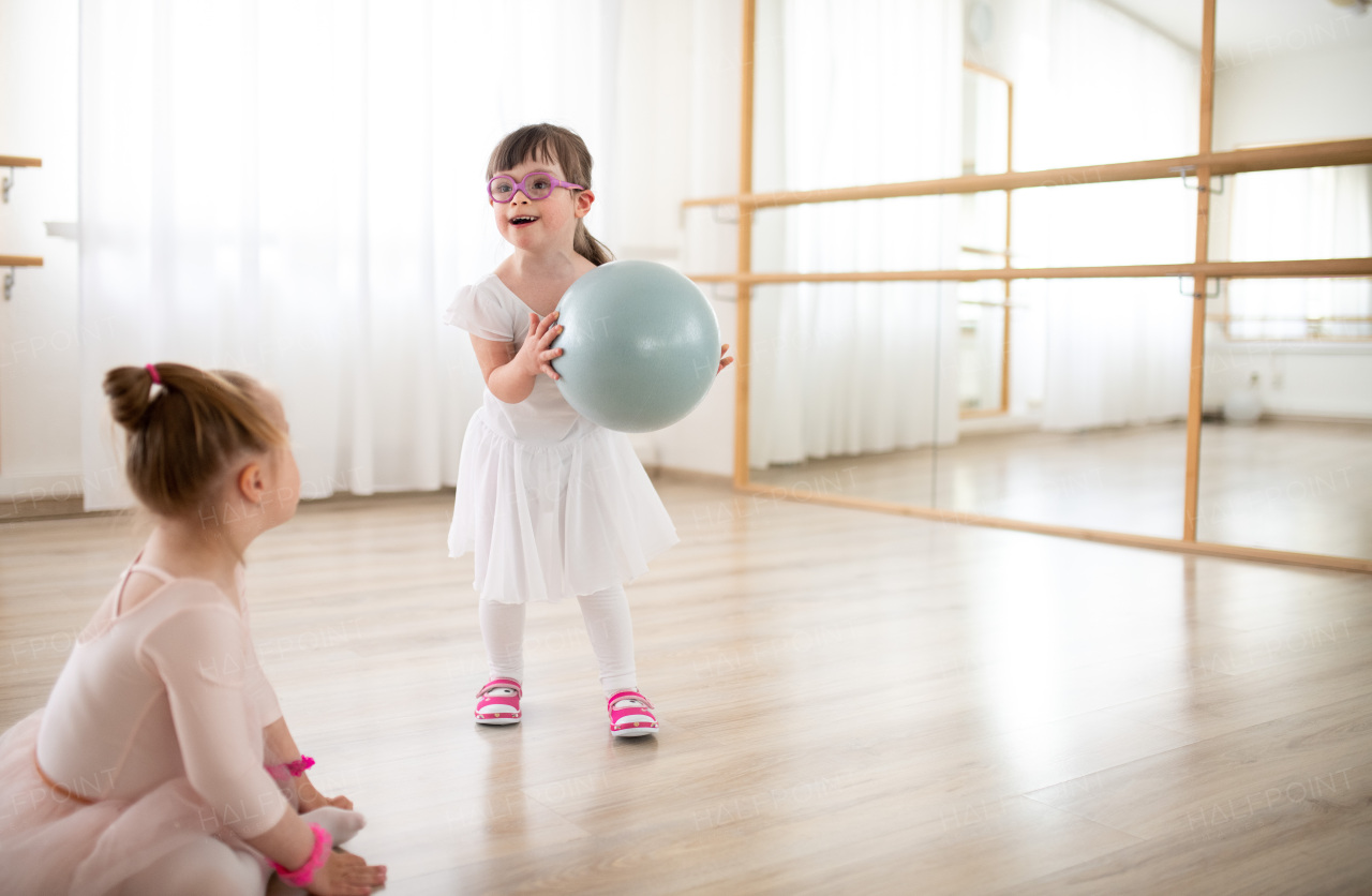 Little sisters with down syndrome dancing ballet in a ballet school studio.