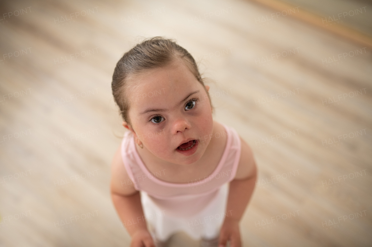 High angle view of little girl with down syndrome at a ballet class in dance studio. Concept of integration and education of disabled children.