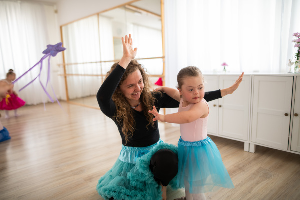 Little girl with down syndrome learning ballet with dance lecteur in a ballet studio.