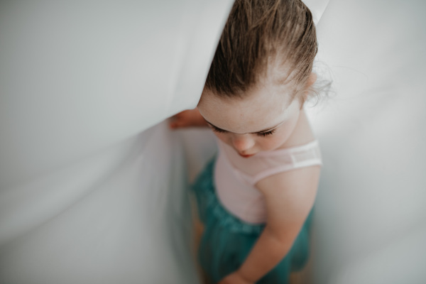 High angle view of little girl with down syndrome at a ballet class in dance studio. Concept of integration and education of disabled children.