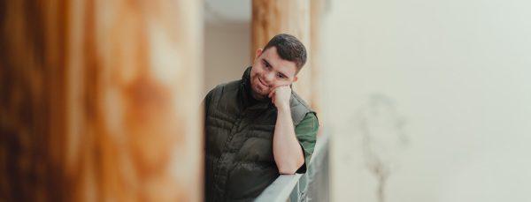 Portrait of pensive man with down syndrome, resting after cleaning animal enclosure in zoo. Concept of integration people with disabilities into society.