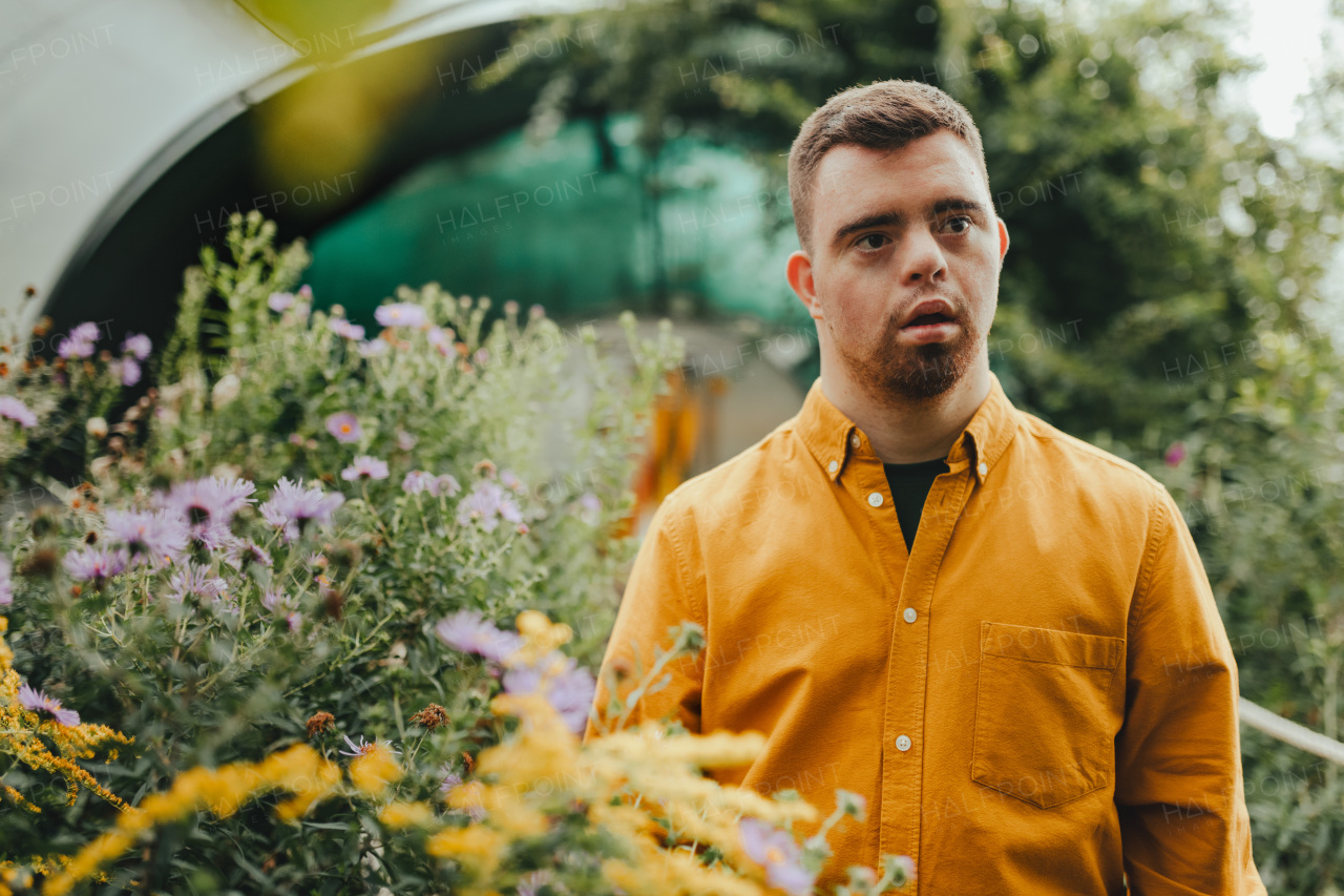 Boy with down syndrome posing with flowers in a garden.