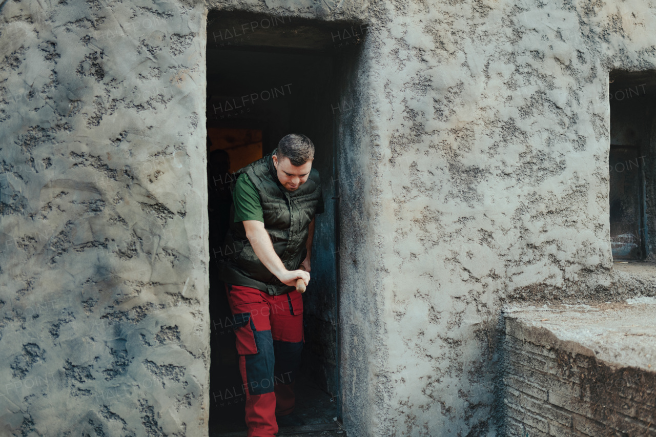 Caretaker with down syndrome in the cleaning animal enclosure. Concept of integration people with disabilities into society.