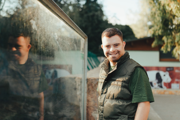 Portrait of caretaker with down syndrome in a zoo. Concept of integration people with disabilities into society.