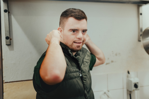 Man with down syndrome working in kitchen in a zoo, prepairing food for animals.Concept of integration people with disabilities into society.