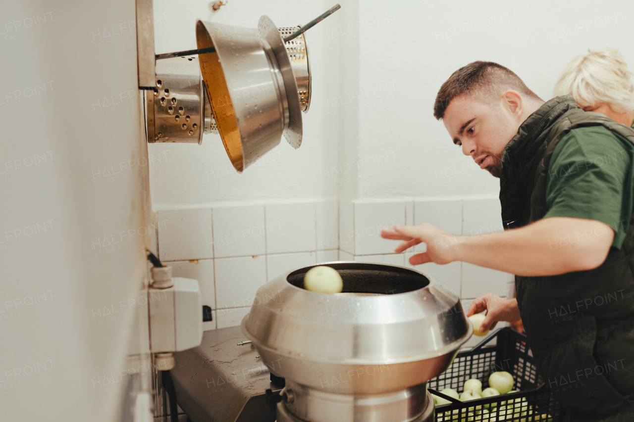 Man with down syndrome working in kitchen in a zoo, prepairing food for animals.Concept of integration people with disabilities into society.