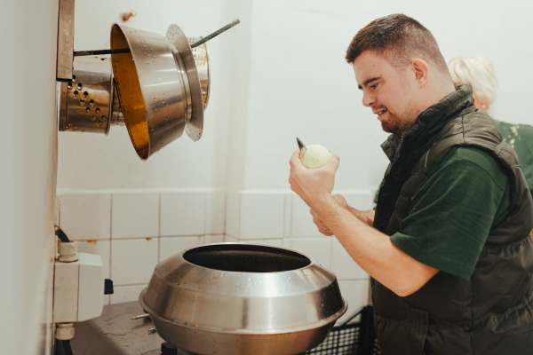 Man with down syndrome working in kitchen in a zoo, prepairing food for animals.Concept of integration people with disabilities into society.