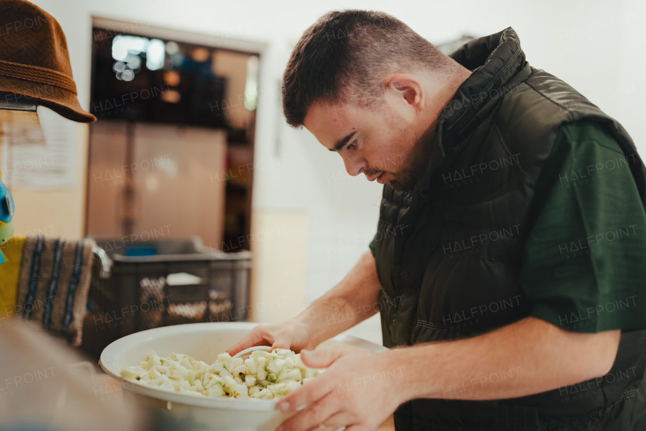 Man with down syndrome working in kitchen in a zoo, prepairing food for animals.Concept of integration people with disabilities into society.