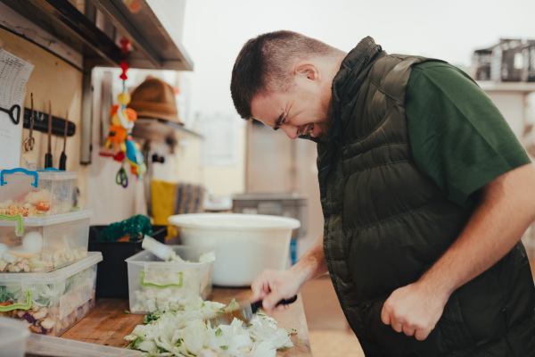 Man with down syndrome working in kitchen in a zoo, prepairing food for animals.Concept of integration people with disabilities into society.