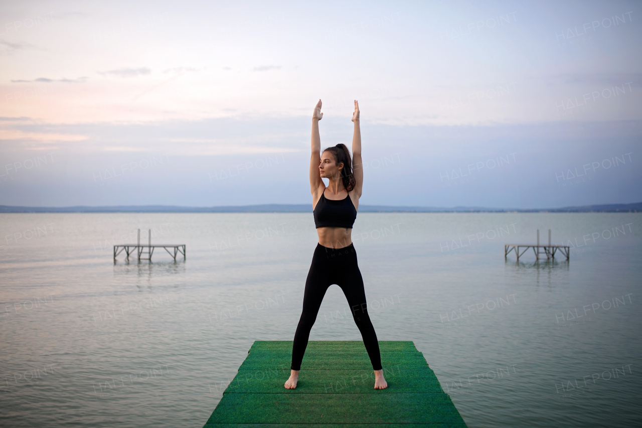 A young beautiful sportive girl training at early morning by the lake.