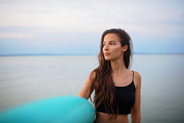 A young beautiful sportive girl with paddleboard on the lake at sunrise