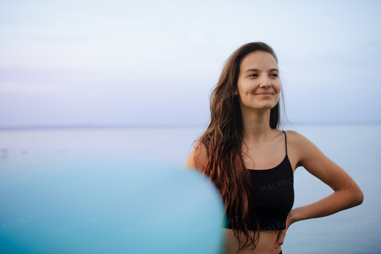 A young beautiful sportive girl with paddleboard on the lake at sunrise