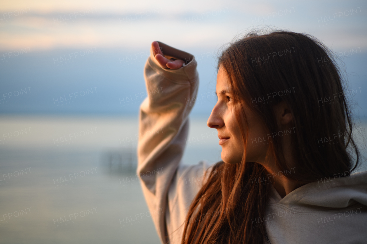 a Young beautiful sportive girl looking at view at sunrise by the lake.