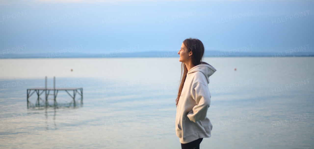 Young sportive girl standing by lake and looking at view.