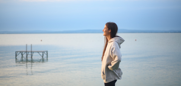 Young sportive girl standing by lake and looking at view.