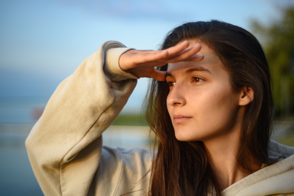 a Young beautiful sportive girl looking at view at sunrise by the lake.