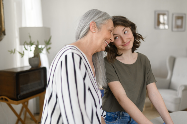 A senior grandmother with teenage granddaguhter having good time together at home.