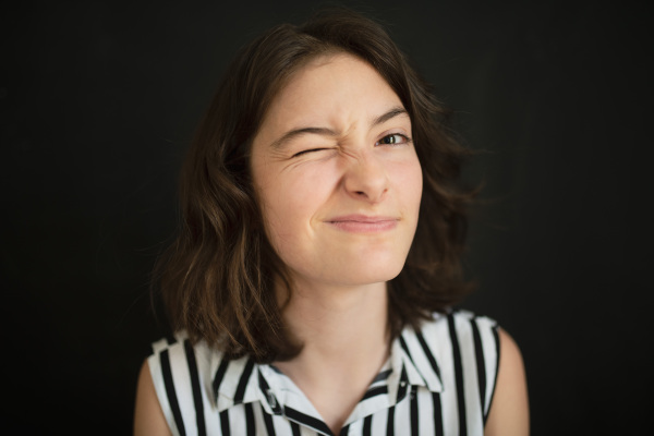 A portrait of happy tennage girl making faces over black background.