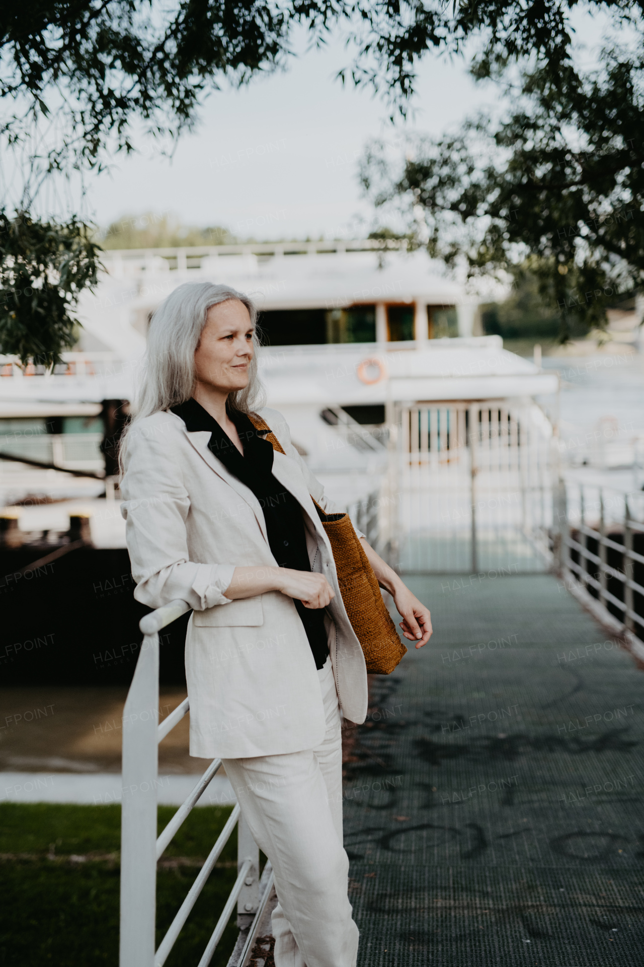 Portrait of a beautiful mature female manager with long gray hair, walking through the city. Middle-aged woman is going for walk in the city to shop.