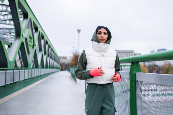 Young muslim woman running outdoor in a city.