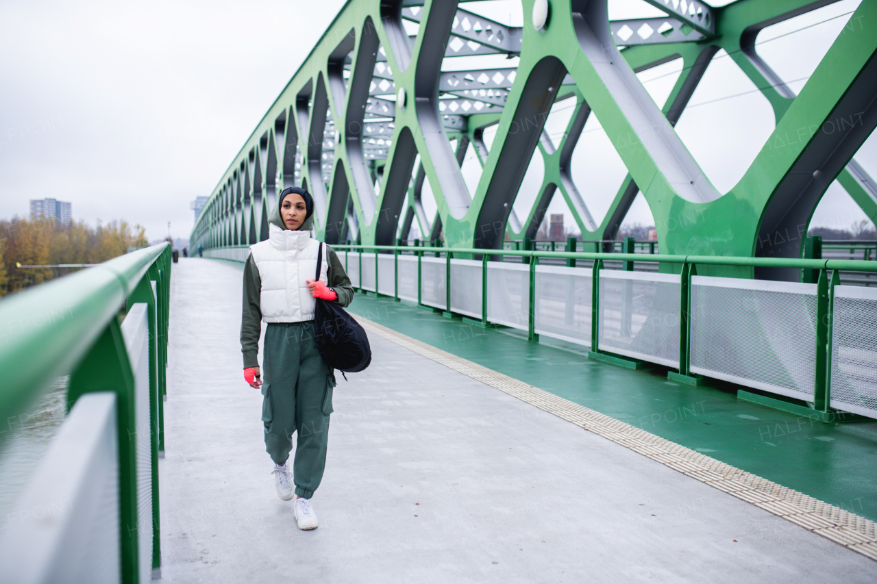 Young muslim woman in sports wear going from box training in a city.