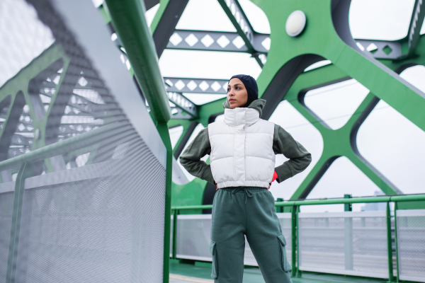 Young muslim woman resting after jogging, outdoor in a city.