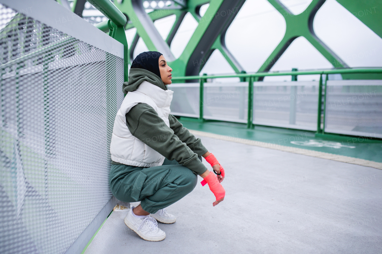 Young muslim woman having break during morning run.