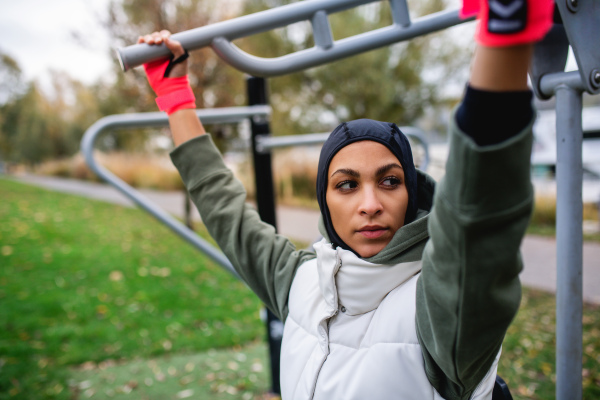 Young muslim woman in a sports hijab doing work out in outdoor training ground.