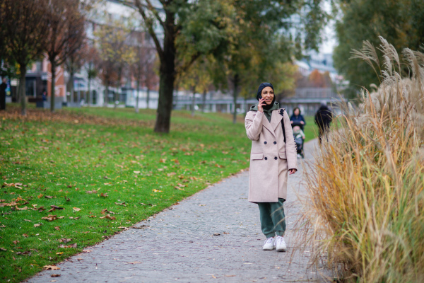 Young muslim woman walking and calling in city.